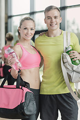 Image showing smiling couple with water bottles in gym