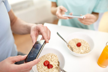 Image showing close up of couple with smartphones at breakfast