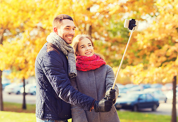 Image showing smiling couple with smartphone in autumn park