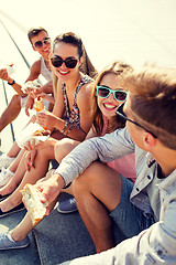 Image showing group of smiling friends sitting on city square