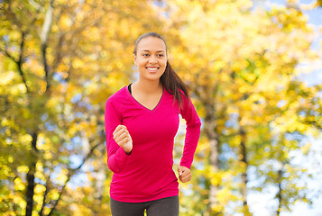 Image showing smiling woman running outdoors at autumn