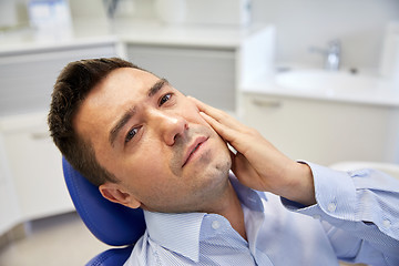 Image showing man having toothache and sitting on dental chair