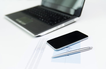 Image showing close up of smartphone, laptop and pen on table