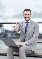 Image showing smiling businessman working with laptop outdoors