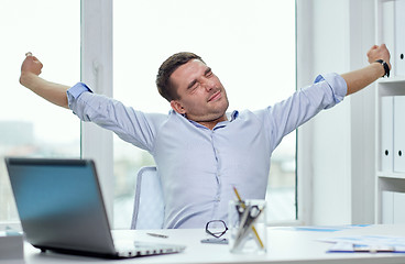 Image showing bored businessman with laptop and papers at office