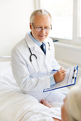 Image showing senior woman and doctor with clipboard at hospital