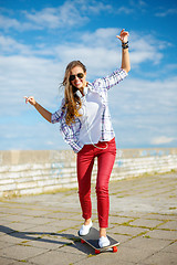 Image showing smiling teenage girl riding skate outside