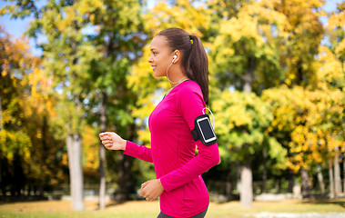 Image showing girl with smartphone and earphones running at park