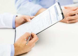 Image showing close up of male doctor and patient with clipboard