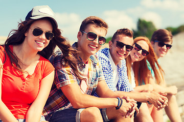 Image showing close up of smiling friends sitting on city street