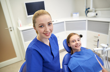 Image showing happy female dentist with patient girl at clinic