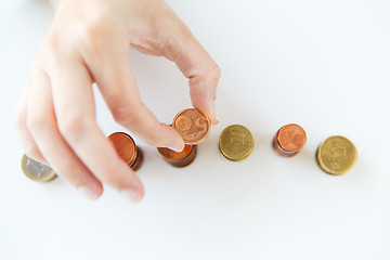 Image showing close up of female hand putting coins into columns