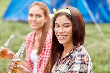 Image showing happy young women with tent and drinks at campsite