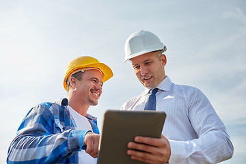 Image showing happy builders in hardhats with tablet pc outdoors