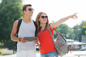 Image showing smiling couple with tablet pc and backpack in city