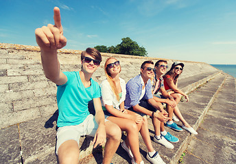 Image showing group of smiling friends sitting on city street