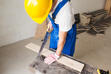 Image showing close up of builder with arm saw sawing board