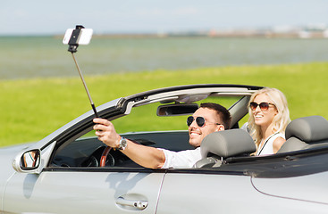 Image showing happy couple in car taking selfie with smartphone