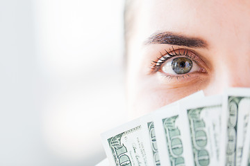 Image showing woman hiding her face behind us dollar money fan