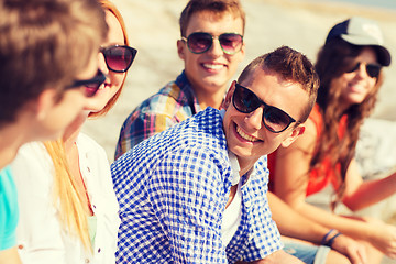 Image showing close up of smiling friends sitting on city street