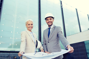 Image showing smiling businessmen with blueprint and helmets