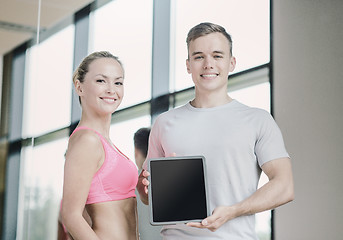 Image showing smiling young woman with personal trainer in gym