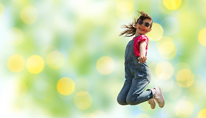 Image showing happy little girl jumping high over green lights