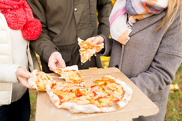 Image showing close up of friends hands eating pizza outdoors