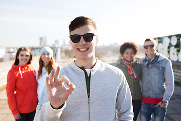 Image showing happy teenage friends showing ok sign on street