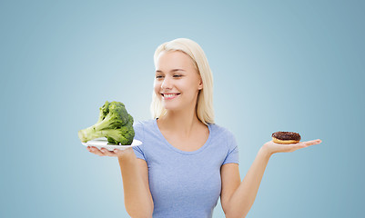 Image showing smiling woman with broccoli and donut