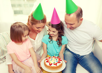 Image showing smiling family with two kids in hats with cake