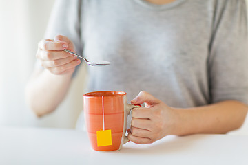 Image showing close up of woman adding sugar to tea cup