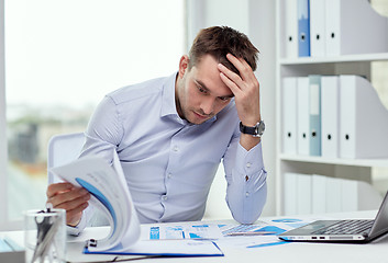 Image showing stressed businessman with papers at office