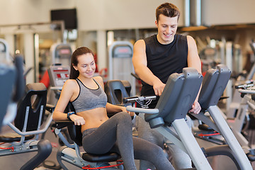 Image showing happy woman with trainer on exercise bike in gym