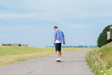 Image showing man with longboard or skateboard riding on road