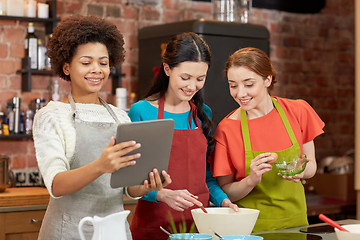 Image showing happy women with tablet pc cooking in kitchen