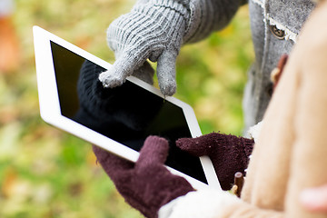 Image showing couple hands in gloves with tablet pc outdoors