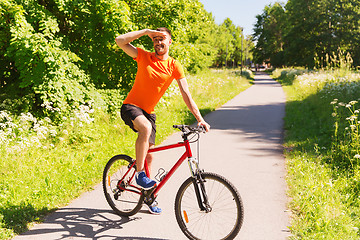 Image showing happy young man riding bicycle outdoors