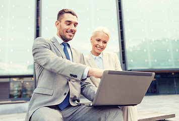 Image showing smiling businesspeople with laptop outdoors