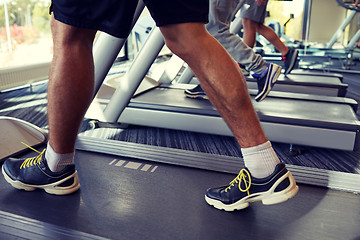 Image showing close up of men legs walking on treadmills in gym
