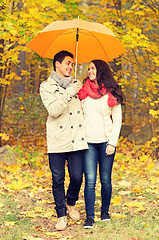 Image showing smiling couple with umbrella in autumn park