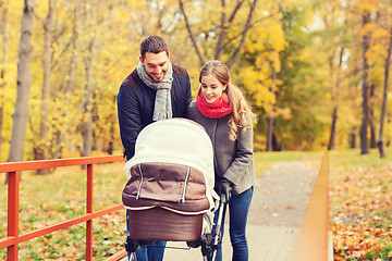 Image showing smiling couple with baby pram in autumn park