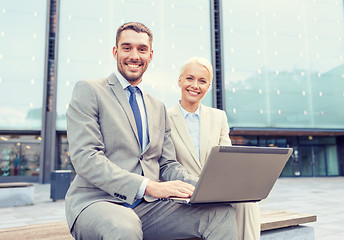 Image showing smiling businesspeople with laptop outdoors