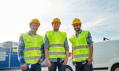 Image showing happy male builders in high visible vests outdoors