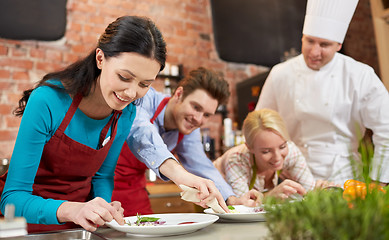 Image showing happy friends and male chef cooking in kitchen