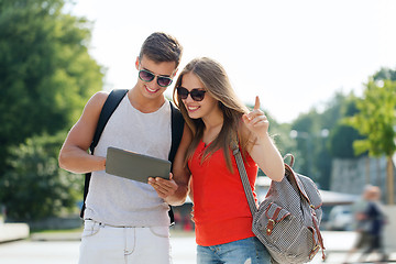 Image showing smiling couple with tablet pc and backpack in city