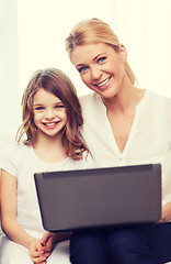 Image showing smiling mother and little girl with laptop at home