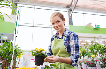 Image showing happy woman holding flowers in greenhouse