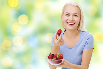 Image showing happy woman eating strawberry