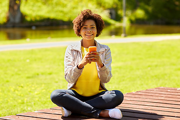 Image showing happy african young woman messaging on smartphone